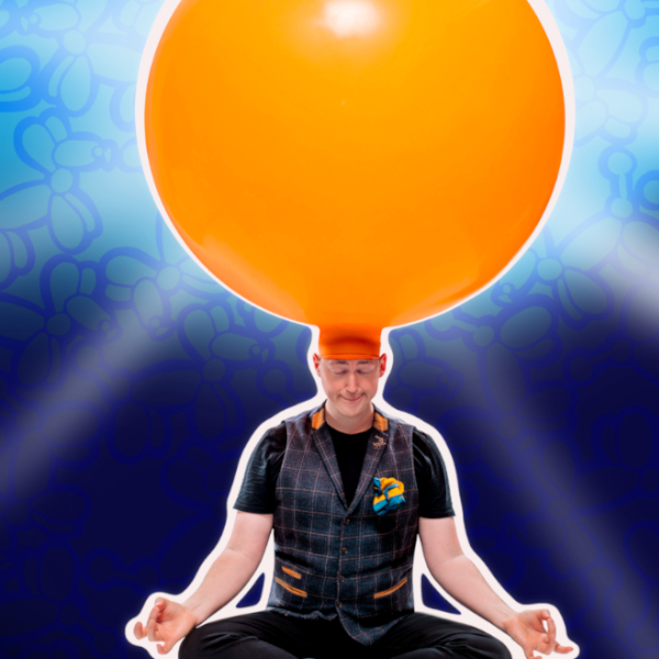 A man sits cross-legged with a huge orange balloon attached to his head
