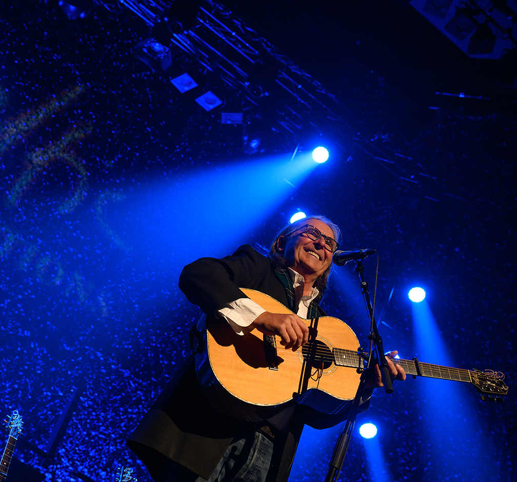 Dougie Maclean smiling holding a guitar