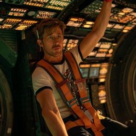 Ryan Gosling seated inside a spaceship wearing a harness